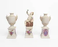 3 kusy bílý porcelán, Nymphenburg, 2 malé amforové vázy s držadly satyrů a malý Bacchus na soudu na podstavci s erbovním kartušem, cca 15 cm a 18,5 cm vysoké