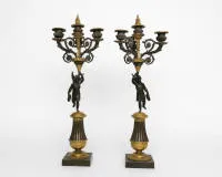 A pair of figurative girandoles / candlesticks, Empire, France, 1st half 19th c., bronze partly gilded, each three-flame, in the shaft a dark patinated sculpture of the winged victory goddess Victoria with laurel wreath, H. 56 cm