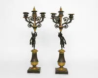Paire de girandoles / bougeoirs figuratifs, Empire, France, 1re moitié 19e s., bronze partiellement doré, chacun à trois flammes, dans la tige une sculpture patinée foncée de la déesse ailée de la victoire Victoria avec couronne de laurier, H. 56 cm