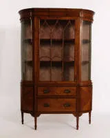 Vitrine de salon Sheraton, Angleterre, vers 1900, placage de bois satiné entre autres, filets ébonisés, corps aux côtés cintrés et vitrage correspondant, porte centrale à croisillons en ogive, deux tiroirs au tiers inférieur...