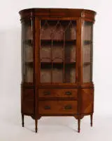 Vitrine de salon Sheraton, Angleterre, vers 1900, placage de bois satiné entre autres, filets ébonisés, corps aux côtés cintrés et vitrage correspondant, porte centrale à croisillons en ogive, deux tiroirs au tiers inférieur...