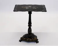 Victorian side table, probably England, 19th c., black-painted wood, the curved top with mother-of-pearl inlay and painted floral still life, top can be raised on baluster shaft over trefoil base, each with ornamental painting...
