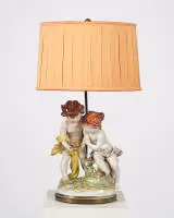 Lampe de salon, « Couple d'enfants avec nid d'oiseau », 20e s., groupe en porcelaine polychrome monté en lampe, deux feux, électrifiée, abat-jour en tissu, 68 cm de haut, fissures