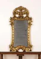 Rococo mirror, gilt frame over red ground in curved rocaille form with sculptural beech leaves in the openwork crest cartouche, 59 x 30 cm