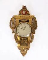 Cartel classique, Suède, fin 18e s., signé Joh. Nyberg Stockholm, boîtier en bois sculpté et doré, riche décor de rinceaux, surmonté d'un médaillon portrait couronné de la reine Frédérique de Suède, cadran blanc...