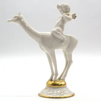 KARL TUTTER. POUR HUTSCHENREUTHER "IDYLL" PUTTO SUR UN CHEVREUIL, DÉTAILS DORÉS, ART DÉCO, ALLEMAGNE.