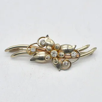 BROCHE DESIGNER, FORME FLORALE, D'APRÈS CLEEF & ARPELS, MONTURE DORÉE, STRASS, VERS 1930-1940.