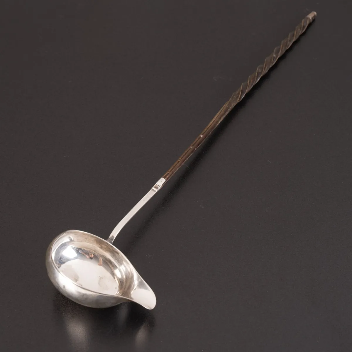 Antike Bowlenkelle, ebonisierter Edelholzgriff mit gedrehtem Abschluss, ungemarkt. 19. / 20. Jhd., Länge ca. 36 cm.