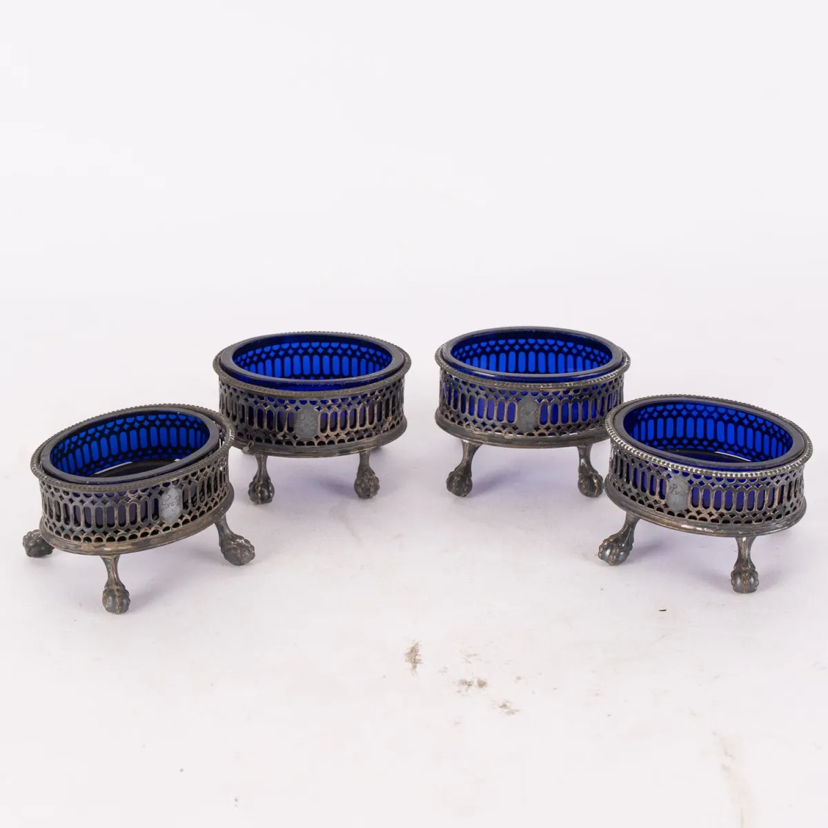 Série de 4 salières, montures argentées, grille frontale avec monogramme gravé au pointillé.