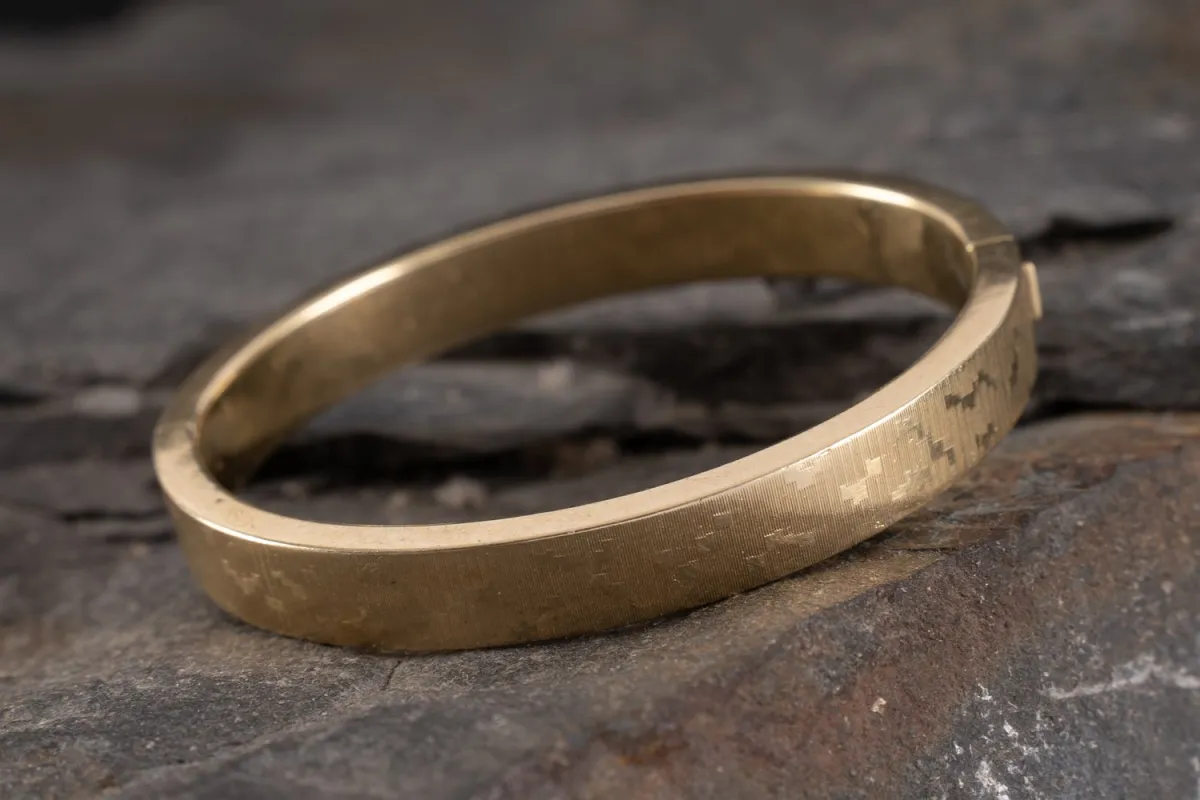 Heavy oval bangle in 585 yellow gold. Hinged with snap clasp. Outer surface chased pattern. Wide…