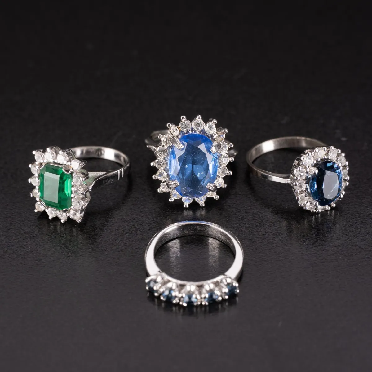 Lot van 4 ringen van onedel metaal met blauwe en groene glasstenen. Verschillende uitvoeringen en maten. Modesieraden…