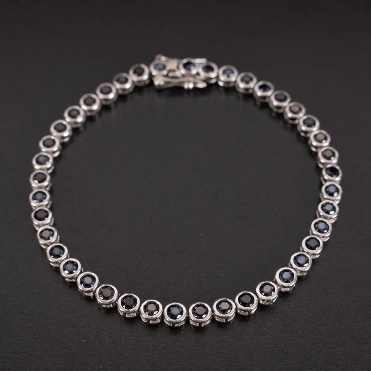 Tennisarmband van 925 zilver, bezet met 41 ronde donkergroene geslepen stenen. Kastsieraad met 2 beveiligingen