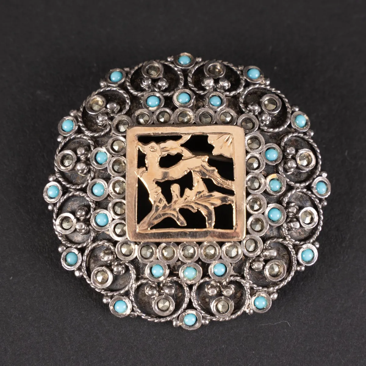 Oudere, interessante, ronde broche van 800 zilver. Bovenzijde fijn ciseleringswerk en bezet met kleine turquoise…