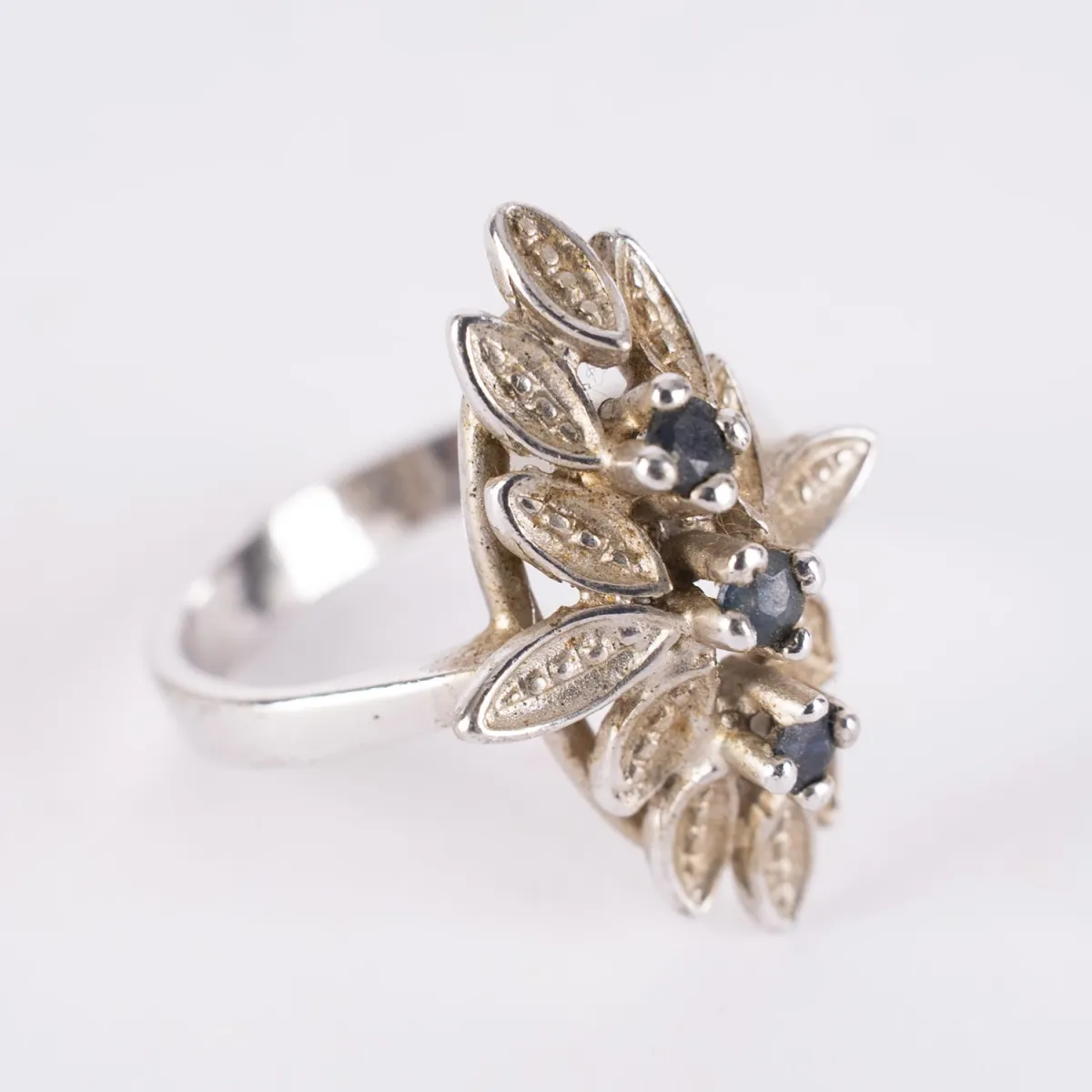 Damesring van 835 zilver. Eenvoudige ringband. De kop in bootvorm met floraal bladwerk en 3 stenen.