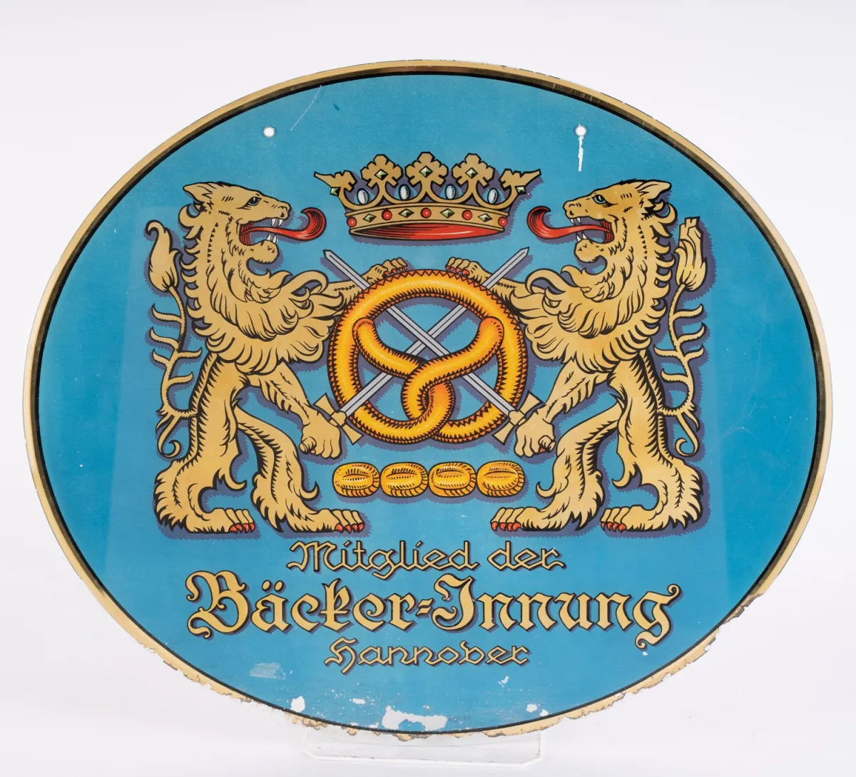 Lid van het Bakkersgilde Hannover - ovaal helder glazen bord, achterzijde bedekt met folie, boorgaten bovenin het midden