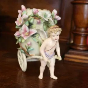 Putto with porcelain egg on cart, H 16cm, marked