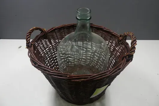 Glass carboy in wicker basket with handles