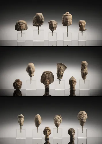 Group of 17 terracottas, mostly head fragments, some mounted on stands