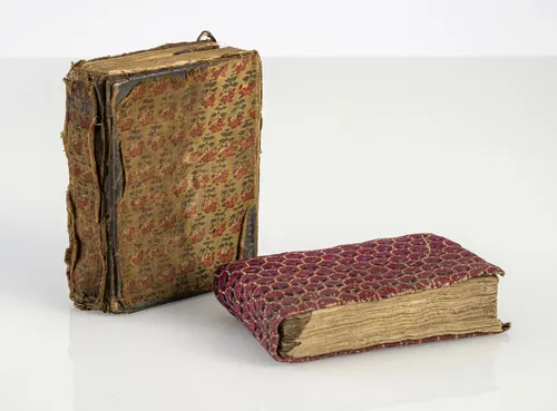 Two books in fabric bindings, partly illustrated with miniatures