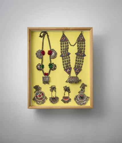 Groep sieraden, o.a. kettingen en oorbellen, deels van zilver, gemonteerd in twee vitrines