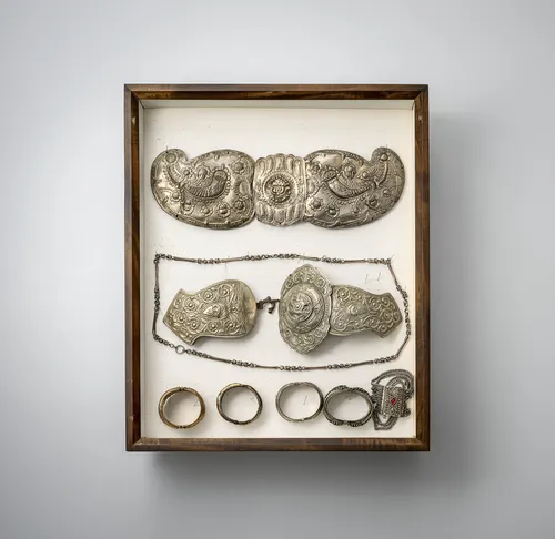 Groep gespen, armbanden en hangers, deels van zilver, gemonteerd in twee vitrines