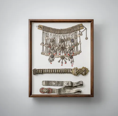 Lot de bijoux, dont pendentifs, ceintures et plaques, en partie en argent, montés dans deux vitrines