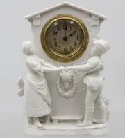 Pendule de table en porcelaine biscuit, mouvement fonctionne, 1x tête de figurine recollée, env. H 17,5 cm L 12,5 cm
