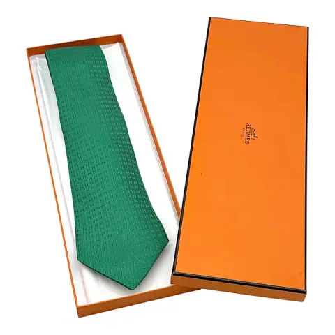 Hermès Paris, Krawatte aus Seide, grün mit eingewebtem Muster aus kleinen „H“, orangefarbener Karton