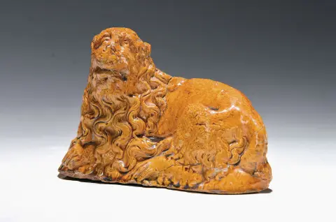 Figurine en grès, probablement 17e s., lion couché à la crinière bouclée, glaçure ocre