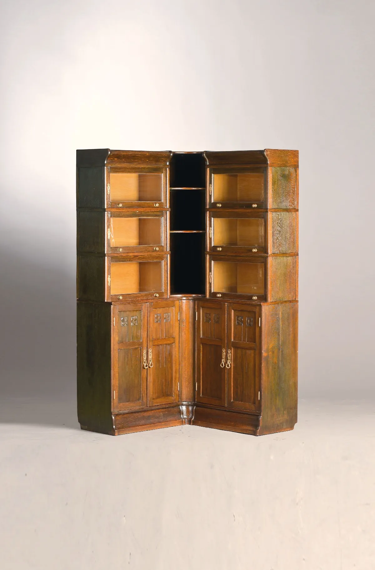 Corner bookcase, circa 1920, dark stained oak, 3-part top with glazed