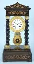 Horloge de portal – bois, teinté brun et partiellement ébonisé, appliques en laiton ornées, 4 colonnes tournées, cadran émaillé, 19e s.