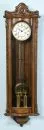 Regulator "Astra" – curved wooden case with carved decorations, glazed on 3 sides, brass movement with enamel dial,…