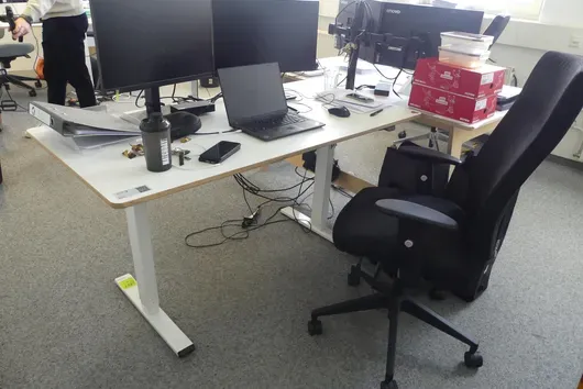 Electrically height-adjustable desk with office chair, without contents