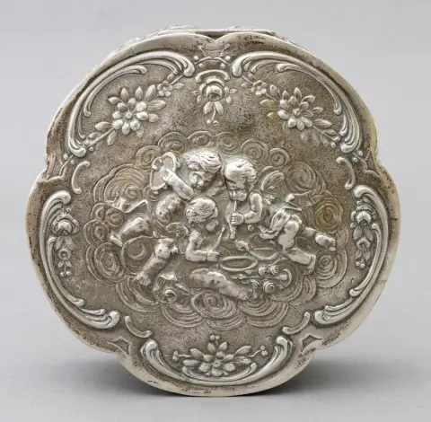 Doos, 800 zilver, Duits, Wilhelm Weinranck & Fritz Schmidt, Hanau, 3e rococo, 1900 - 1950 decor van bloemen, rozenbloesems, rocailles en talrijke, deels musicerende putti. Deksel met scharnier. D 16 cm, H 6,3 cm, gewicht 400 g. Op de bodem gemerkt: 800, halve maan, kroon en meesterteken WSH in hart.