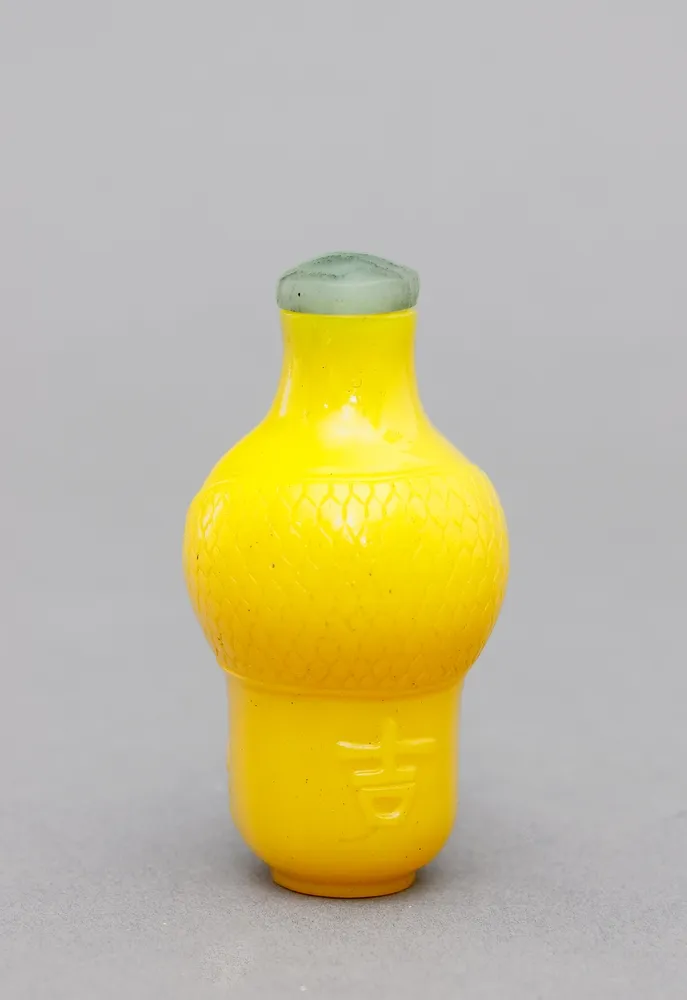 China, Suffbottle, Pekinglas, Qing Balusterform in Kaiser-Gelb mit ornamentalem Relief und Bezeichnung wohl "Da Gù". Stopper als flach…