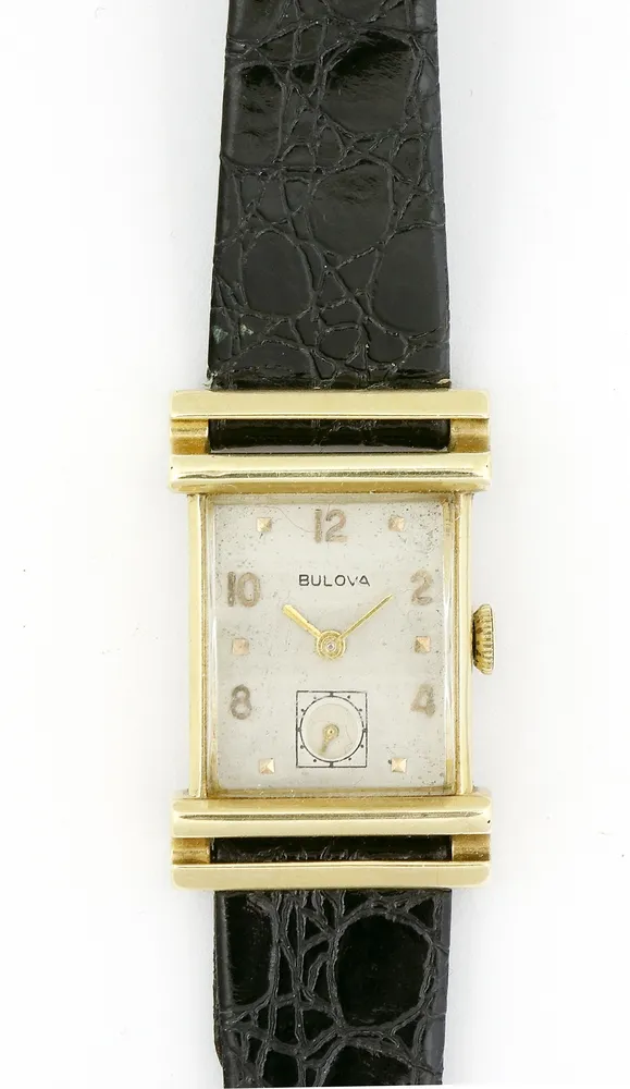 Watch, wristwatch, 14K gold, Bulova, circa 1950, rectangular case with gold profile, silver dial with 2,4,6,8,10,12 numerals, small seconds at 6. Manual wind. Leather strap. Back marked 14K gold, Bulova, 9724980. 3.5 x 2.6 cm. Runs, long-term function not tested.