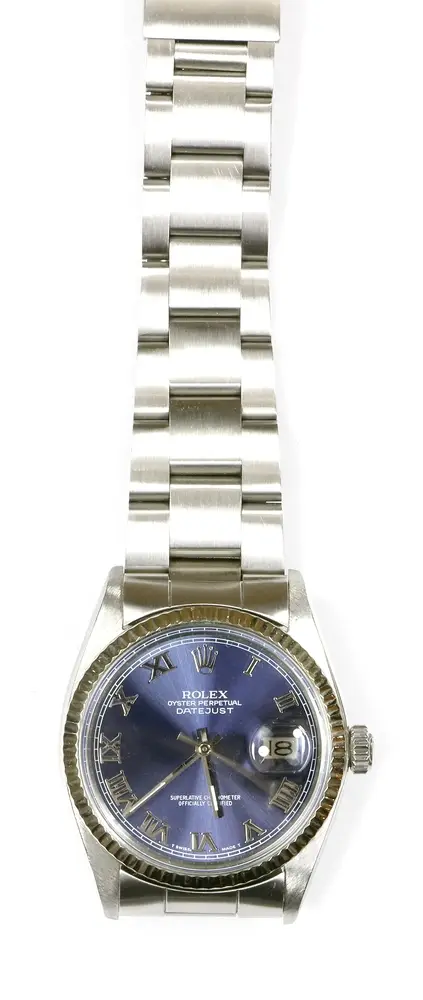 Montre, bracelet, Rolex, acier, Oyster Perpetual, Date Just Superlative Chronometer Officially Certified. Bracelet en acier à maillons. Cadran bleu foncé chatoyant avec date et chiffres romains. Lunette cannelée en or blanc, 18 carats. Diamètre env. 34 mm. Fonctionne, durabilité non testée. Dans étui d'origine. Facture disponible.